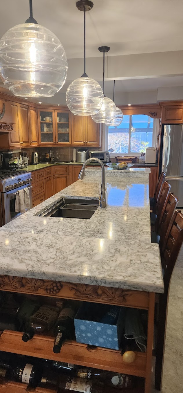 Granite kitchen island with natural stone movement, pendant lights, and sink
