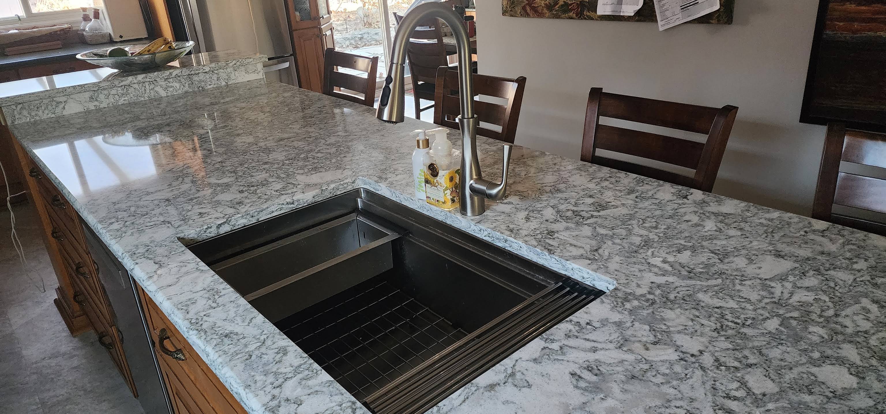 Close-up of granite island sink cutout, faucet line, and rich stone surface
